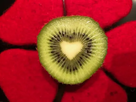 Coeur de kiw en coupei en forme de coeur sur pétales rouges